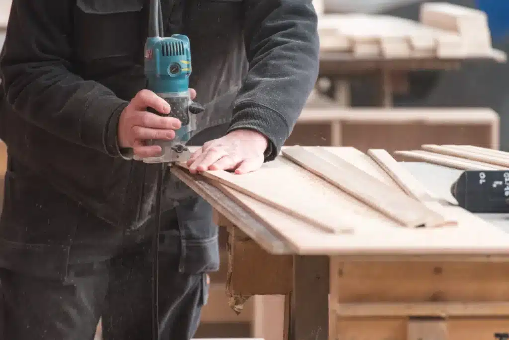 amenagement-interieur-menuisier Artisan menuisier utilisant une défonceuse pour préparer des éléments en bois destinés à l'aménagement intérieur