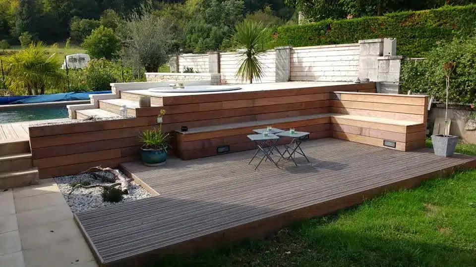Terrasse Bois Luxe : Jacuzzi, Banquette et Aménagement Terrasse en bois moderne avec jacuzzi encastré, banquette d'angle, et petit salon d'extérieur, jouxtant une piscine et un jardin verdoyant.
