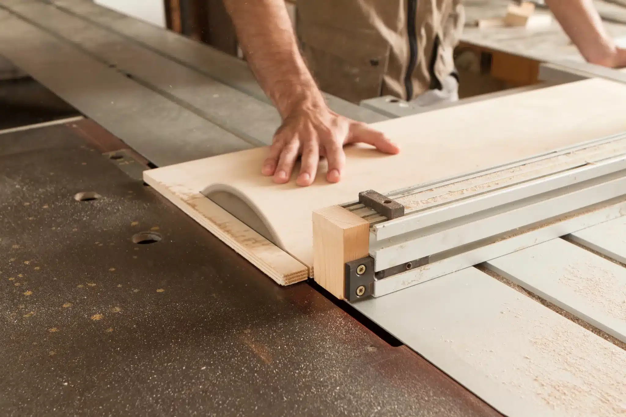 Menuisier effectuant une coupe de précision sur un panneau de contreplaqué avec une scie circulaire de table, utilisant une règle et un guide.