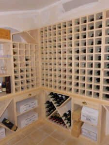 Cave à vin en bois clair non terminée, remplie de casiers cubiques pour bouteilles et de zones de stockage pour caisses (ROC DE BERNON 2008, CHATEAU MOULIN DE CLOTTE, CHATEAU BELLEVUE).