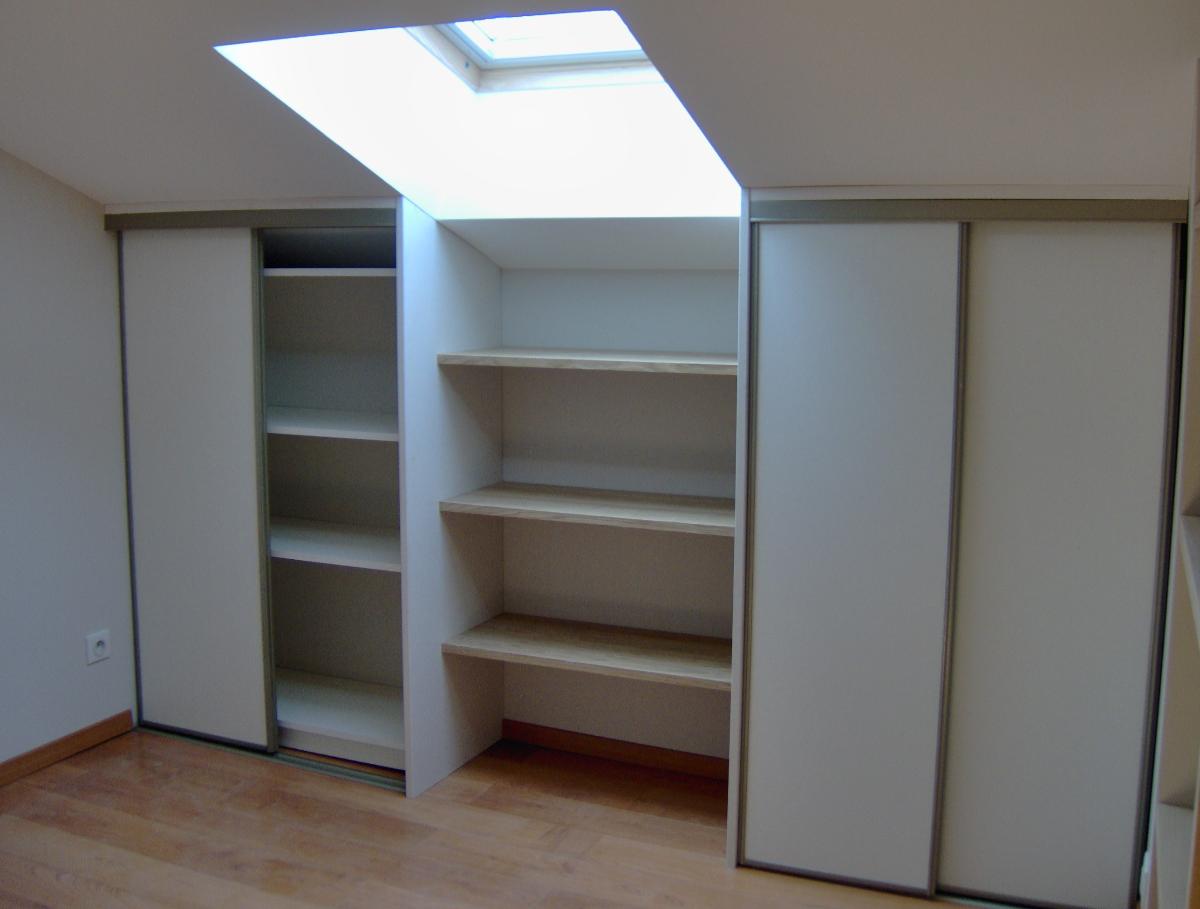 Aménagement de rangement sous une lucarne de toit, avec étagères ouvertes au centre et placards à portes coulissantes blanches sur les côtés.